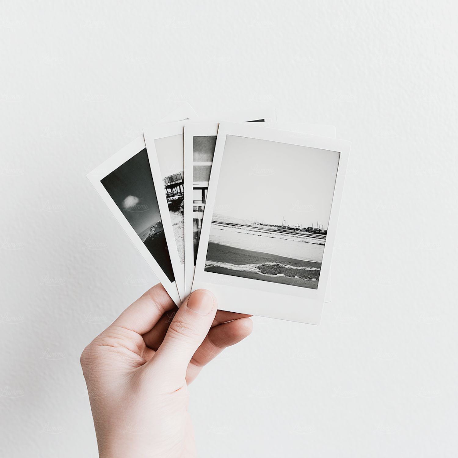 A hand holding a set of small monochrome landscape prints